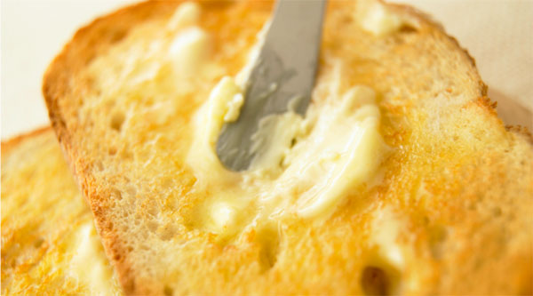 A close-up of golden butter being slowly churned in a small creamery vat